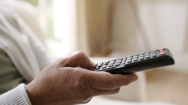 一个女人拿着电视遥控器在家休息的照片图片下载