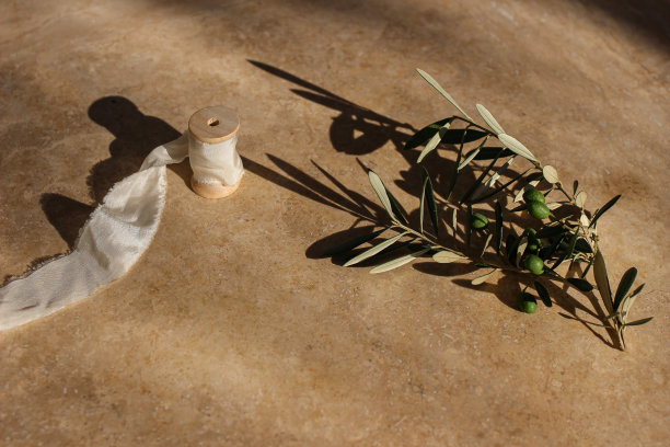 夏季婚礼静物场景。日出的阳光下，金色大理石背景上的橄榄枝和丝绸缎带。严厉的长长的影子。喜怒无常的生活照片。前视图。地中海,忧虑的概念图片下载