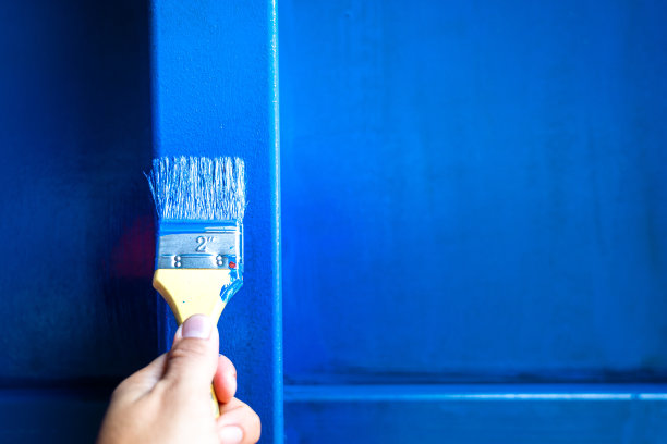 画家拿着画笔在金属表面物体上作画。图片下载