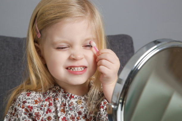 3岁的小女孩在镜子前玩化妆品图片下载