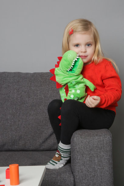 可爱的3岁女孩玩手毛绒木偶恐龙。用于创造力和情感发展的软性教育玩具。图片下载