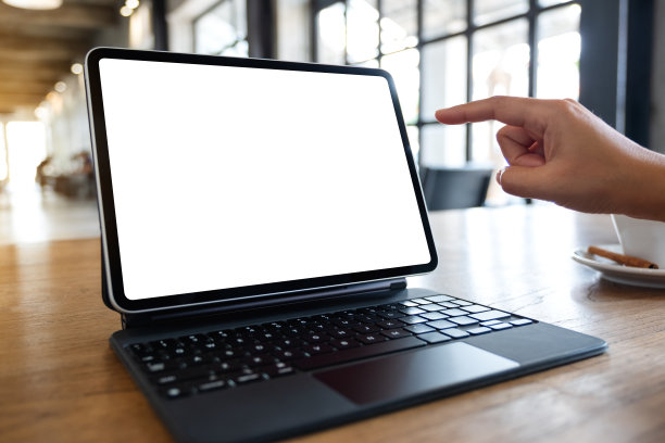 一位女士在咖啡馆里指着并触摸着空白桌面屏幕上的数字平板电脑图片下载