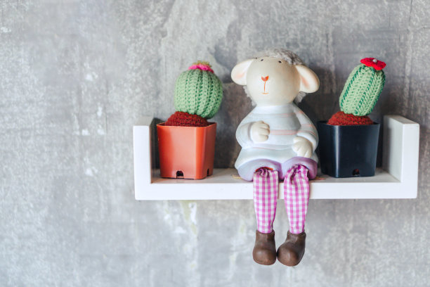 绵羊娃娃坐在木地板上。装饰性的羊图片下载