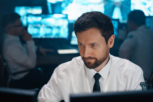 一个40多岁的男人的特写，留着胡子，坐在他的办公桌前。图片下载