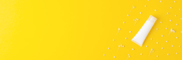 白色的化妆品管与花在黄色的背景。平铺，拷贝空间图片下载