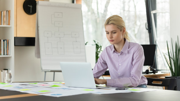 自信的年轻女商人坐在办公桌前用笔记本电脑工作图片下载