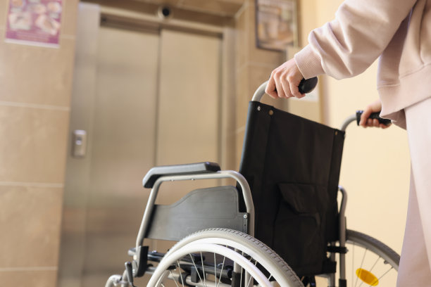 女人推着轮椅到电梯去见残疾人图片下载