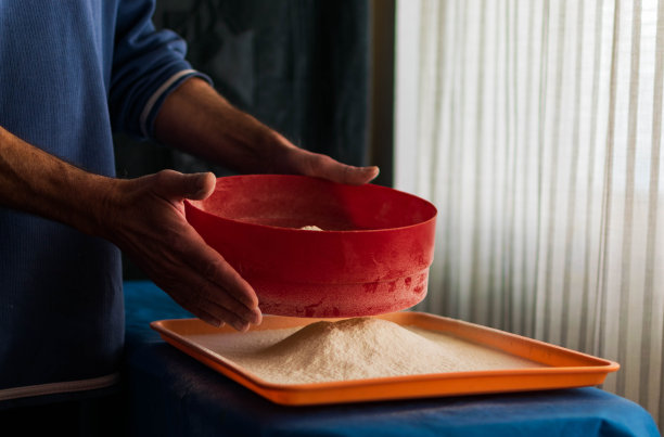 一个人用筛子筛面粉。图片下载