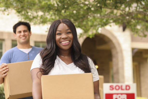 兴奋的年轻夫妇把箱子搬到他们的新家。图片下载