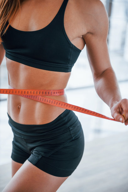 近距离观察妇女的运动身体与测量带周围的腰部图片下载