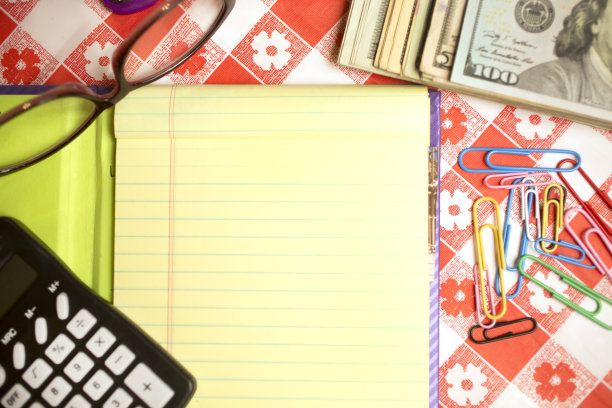 厨房桌子上有记事本，计算器，现金，眼镜，回形针和订书机。计算再融资决策。图片下载