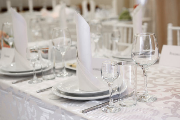 餐桌上有亮晶晶的酒杯，配有白色餐巾和餐具的盘子，复印空间。地点定在婚宴上。餐厅婚宴餐桌图片下载