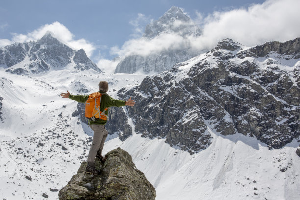 一个徒步旅行者张开双臂站在山顶上图片下载