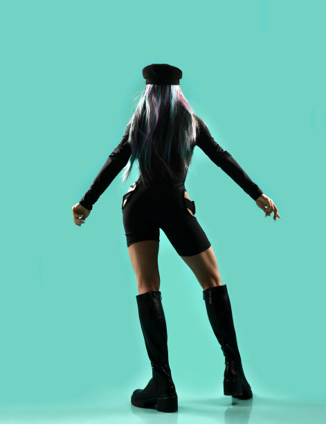 金发年轻女子，有色头发背对着镜头，举起手。宪兵连身衣，手枪。帽。残酷的靴子图片下载