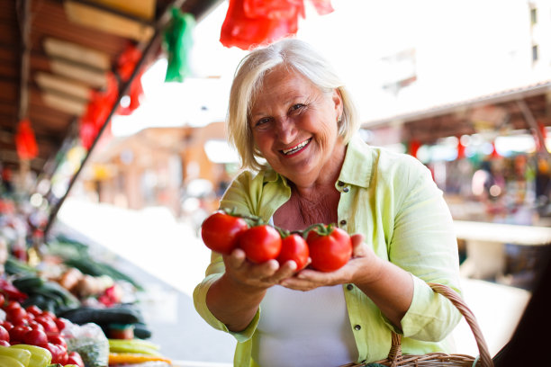 老妇人捧着西红柿，满意地购买。图片下载