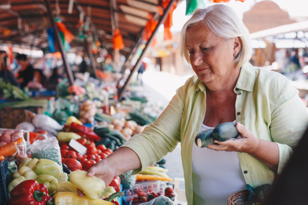 老妇人在农贸市场买新鲜蔬菜。图片下载