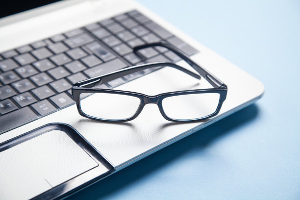 笔记本电脑键盘上戴着黑色眼镜。图片下载