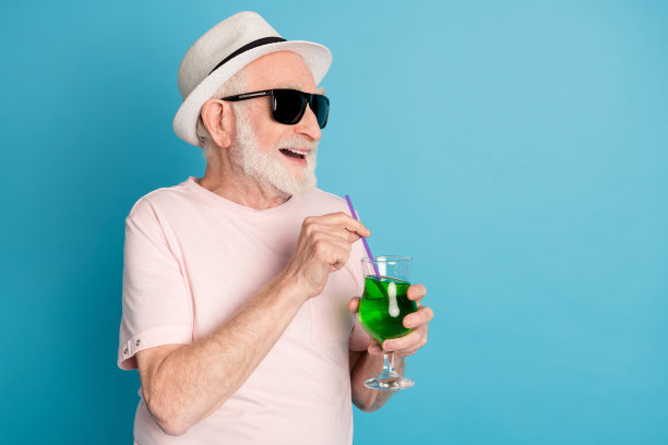老人的侧面照片快乐积极的微笑喝鸡尾酒看起来空荡荡的孤立的蓝色背景图片下载