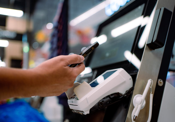 一名亚洲男子在商店用智能手机付款图片下载