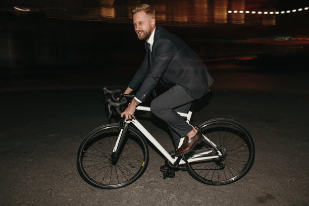 快乐的商人在夜晚的城市骑自行车图片下载