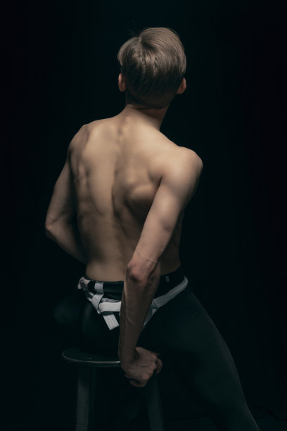 肖像年轻英俊的男子，时装模特摆出孤立在黑暗的背景。美丽、时尚、灵感概念。图片下载