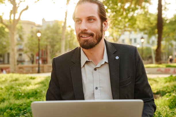 照片的特写是一个扎着头发的帅气的商人，在一个阳光明媚的日子里在城市公园里休息图片下载