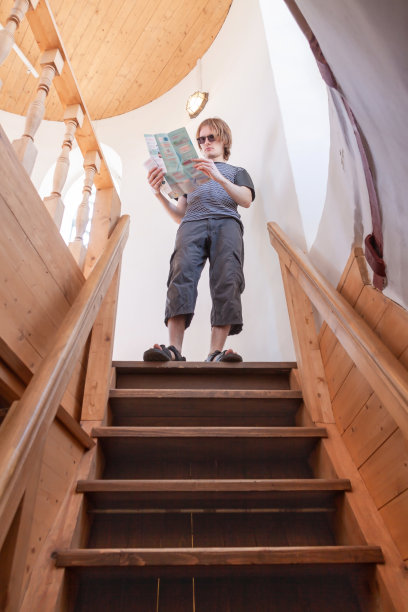 一个年轻的观光客在楼梯顶端看地图。单独旅行的概念图片下载