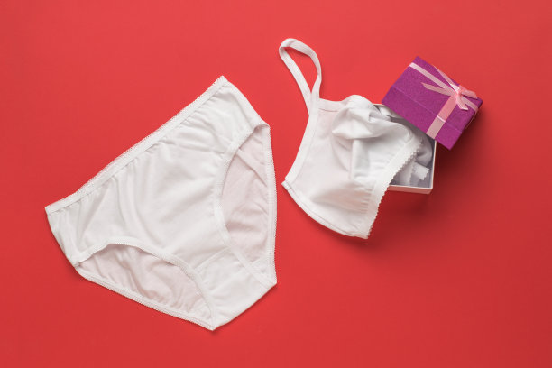红色背景的礼品盒里的女性内衣。平的。图片下载