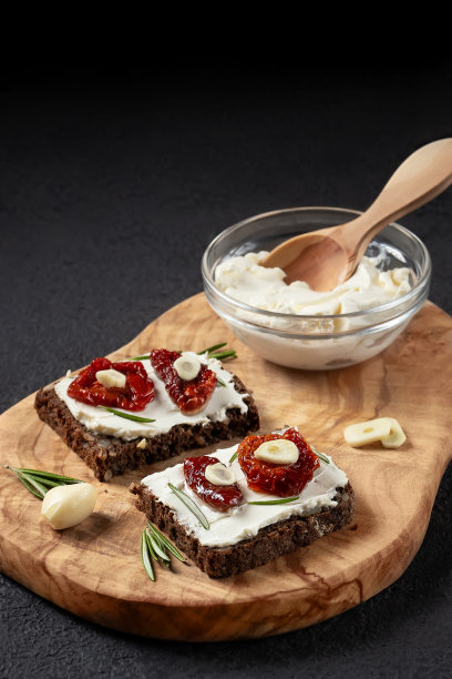 自制杂粮面包三明治，奶油芝士和晒干的西红柿放在木盘子上。健康饮食的概念。垂直横幅，复制空间图片下载