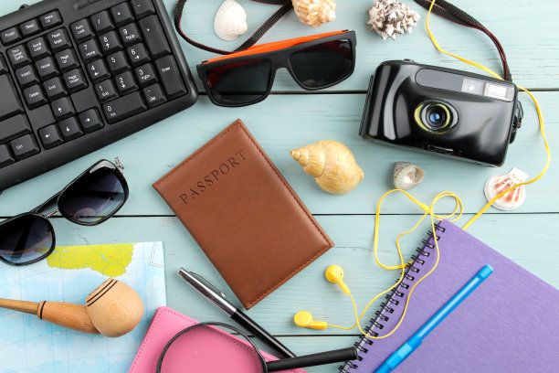 蓝色木桌上放着眼镜、相机、护照、地图和贝壳。放松。假期。俯视图图片下载