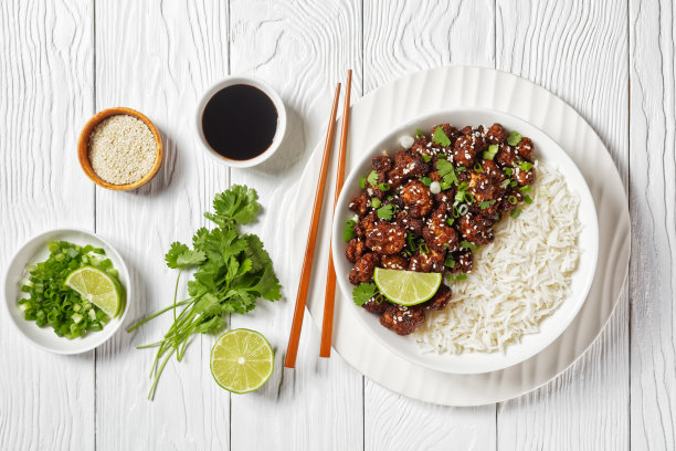 照烧酱汁花椰菜鸡翅——纯素烤花椰菜，涂上棕色酱汁，上面撒上新鲜的香菜、芝麻籽，再配上柠檬和米饭，俯视图图片下载