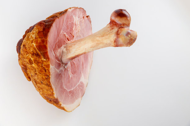 在白色孤立的背景上有大骨头的上釉猪肉火腿。图片下载