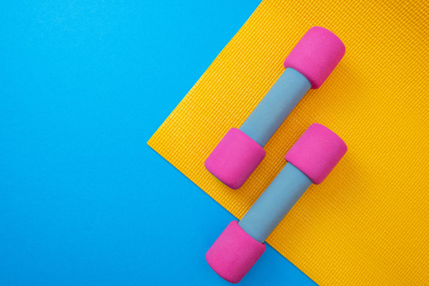 黄色的垫子和粉色的哑铃，蓝色的背景和特写图片下载