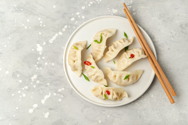 美味的饺子饺子蒸在白色盘子上，酱油和辣椒酱图片下载