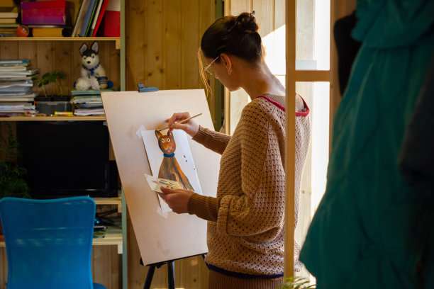 在窗边的一个小工作室里，艺术家用丙烯颜料在画架上画了一只猫图片下载