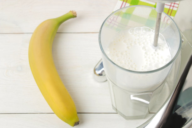 做奶昔。混合奶昔和香蕉在一个明亮的背景。特写镜头图片下载