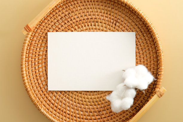 白色邀请卡模型与棉花藤板上米黄色的背景。平躺，俯视图。图片下载