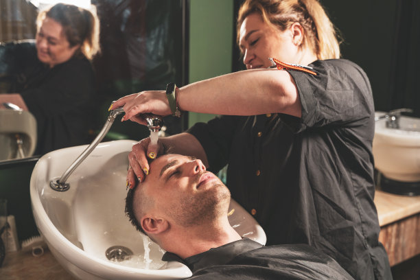 理发:在一家理发店里，女理发师给一个小伙子洗头图片下载