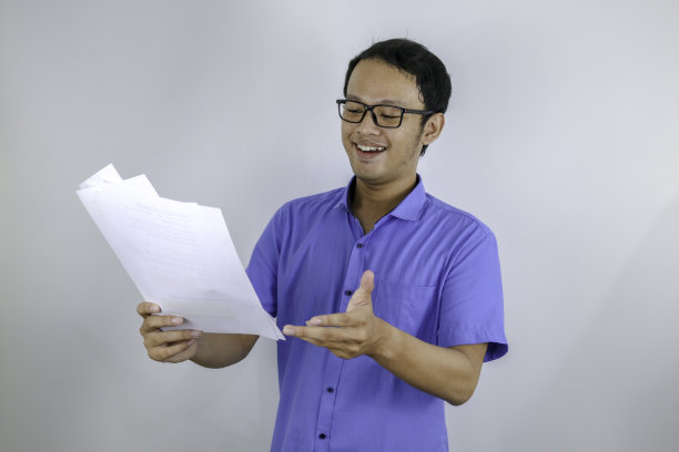 年轻的亚洲人是微笑和快乐的时候，看文件。身穿蓝色衬衫的印尼男子。图片下载