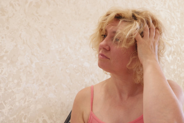 一个女人醒了过来，摸了摸自己的头发和脸。图片下载