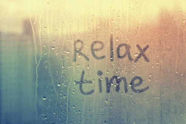 雾蒙蒙的玻璃在窗户上写着手指字放松时间在泥泞的蓝色玻璃上湿的橙色窗户在城市上的日落图片下载