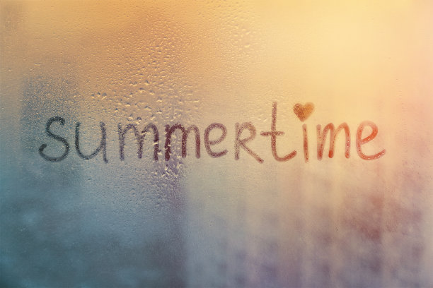 雾蒙蒙的玻璃在窗户上用手指写着夏天的时间在泥泞的蓝色玻璃上，潮湿的橙色窗户在城市上的日落图片下载