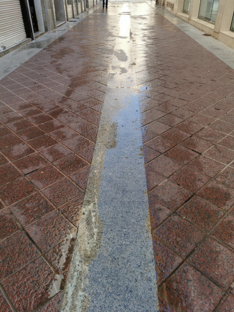 雨后的孤立水坑的近距离观察，反映了街道上的房屋立面图片下载