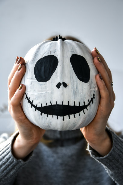 一个女人把滑稽的南瓜脸举在面前。万圣节背景Diy。自己动手图片下载