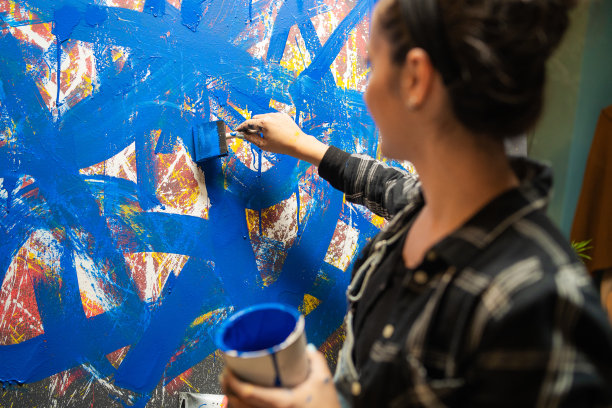才华横溢的艺术家用蓝色颜料绘制油画，用轻柔小心的手拖动动作。画中央的一幅画被一个女人轻轻地涂抹了图片下载