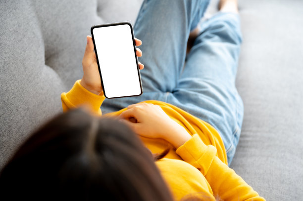 模拟图像白屏移动智能手机。女人在用智能手机，在沙发上放松。剪切路径包括设备屏幕图片下载