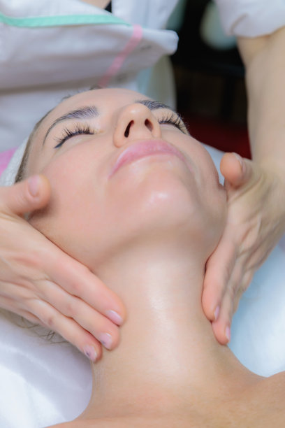 这个女孩在美容院接受脸部和颈部按摩。图片下载