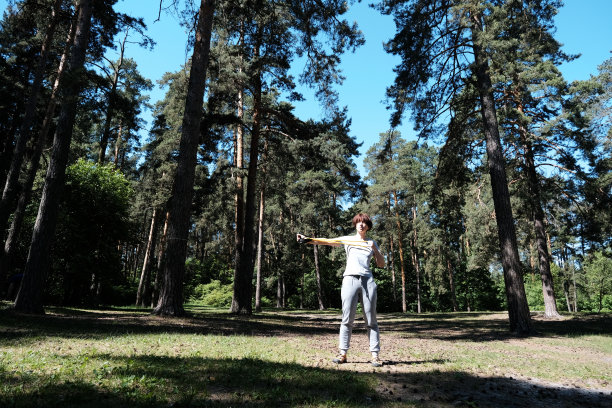 成熟的女人在松林里与阻力带一起锻炼图片下载