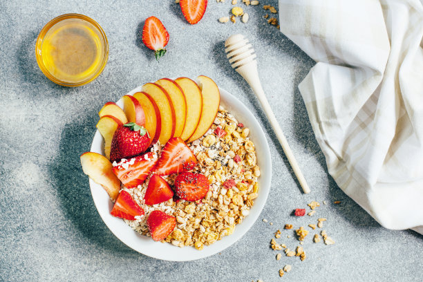 俯视图的早餐粥燕麦燕麦片干果，草莓，桃子，蜂蜜在一个灰色的背景图片下载