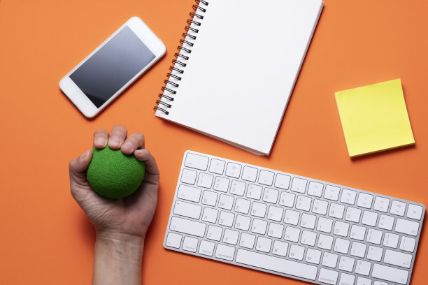 靠近电脑，压力球和键盘电脑与橙色的桌子背景在办公室，压力概念图片下载